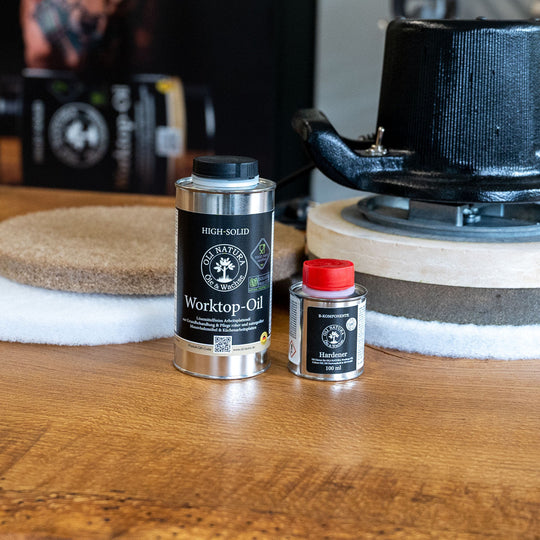 OLI-NATURA Worktop-Oil und Hardener neben einer Poliermaschine auf einer Holzplatte